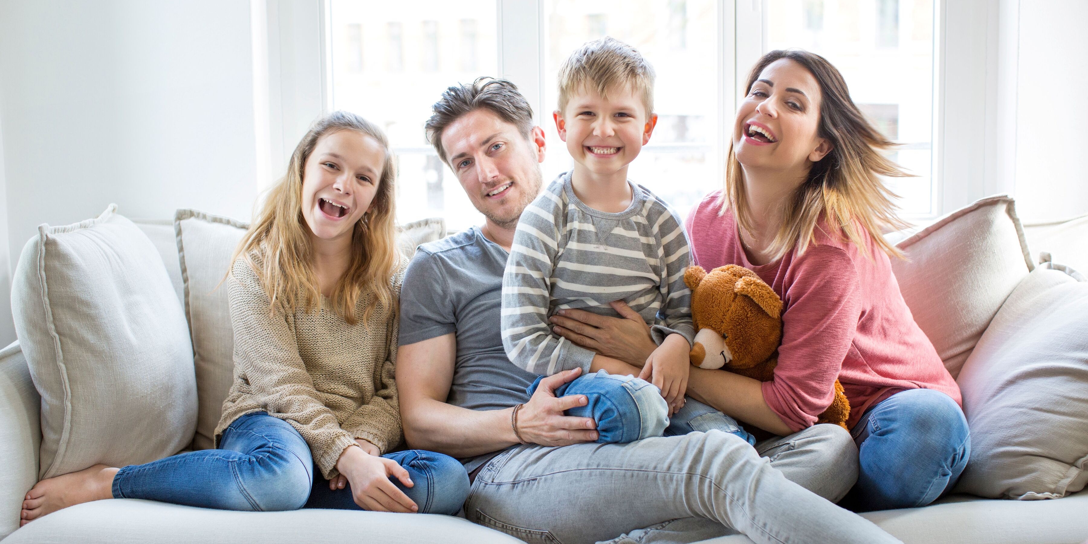 Glückliche Familie sitzt in ihrem Wohnzimmer auf einem Sofa.